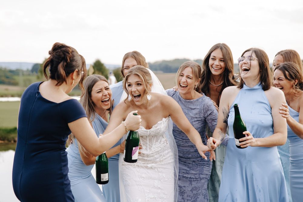 Die Braut lacht mit ihren Freundinnen und Sekt